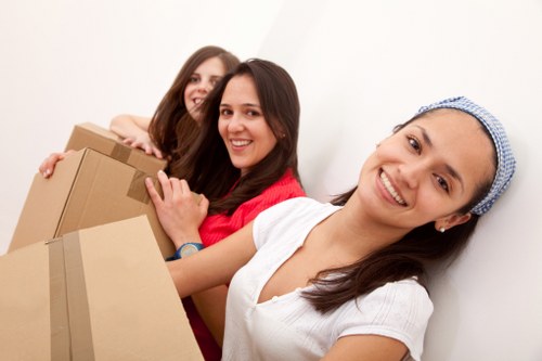 Professional movers carrying furniture through a narrow hallway in Earls Court